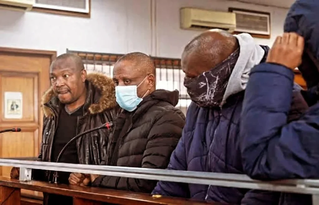 Four accused people in court wearing a mask.
