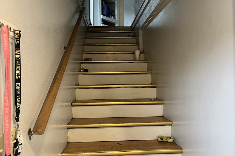 Shot of the stairs. Four empty cans and a takeout drink are on the stairs. Two lanyards are hanging on the rack, pink and black, of the University of Idaho.Moscow Police Department