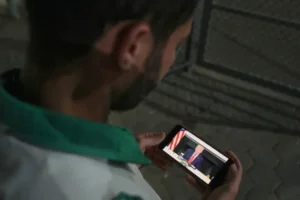 Palestinian paramedic Saeed Awad looks at his phone displaying an image of President Donald Trump following the Gaza deal announcement as he stands at Al-Aqsa Hospital in Deir al-Balah in Gaza on Wednesday. Image Credit: Abdel Kareem Hana/AP