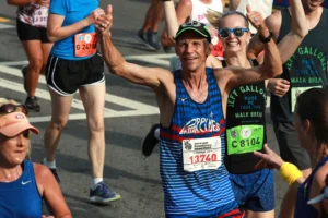 Jeff Galloway gives a double thumbs-up as he heads to the finish line in the 50th AJC Peachtree Road Race in Atlanta in 2019. Galloway won the race in its first year.Curtis Compton / AP file