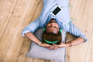 Young Afro American man lying on floor with headphones and smart phone